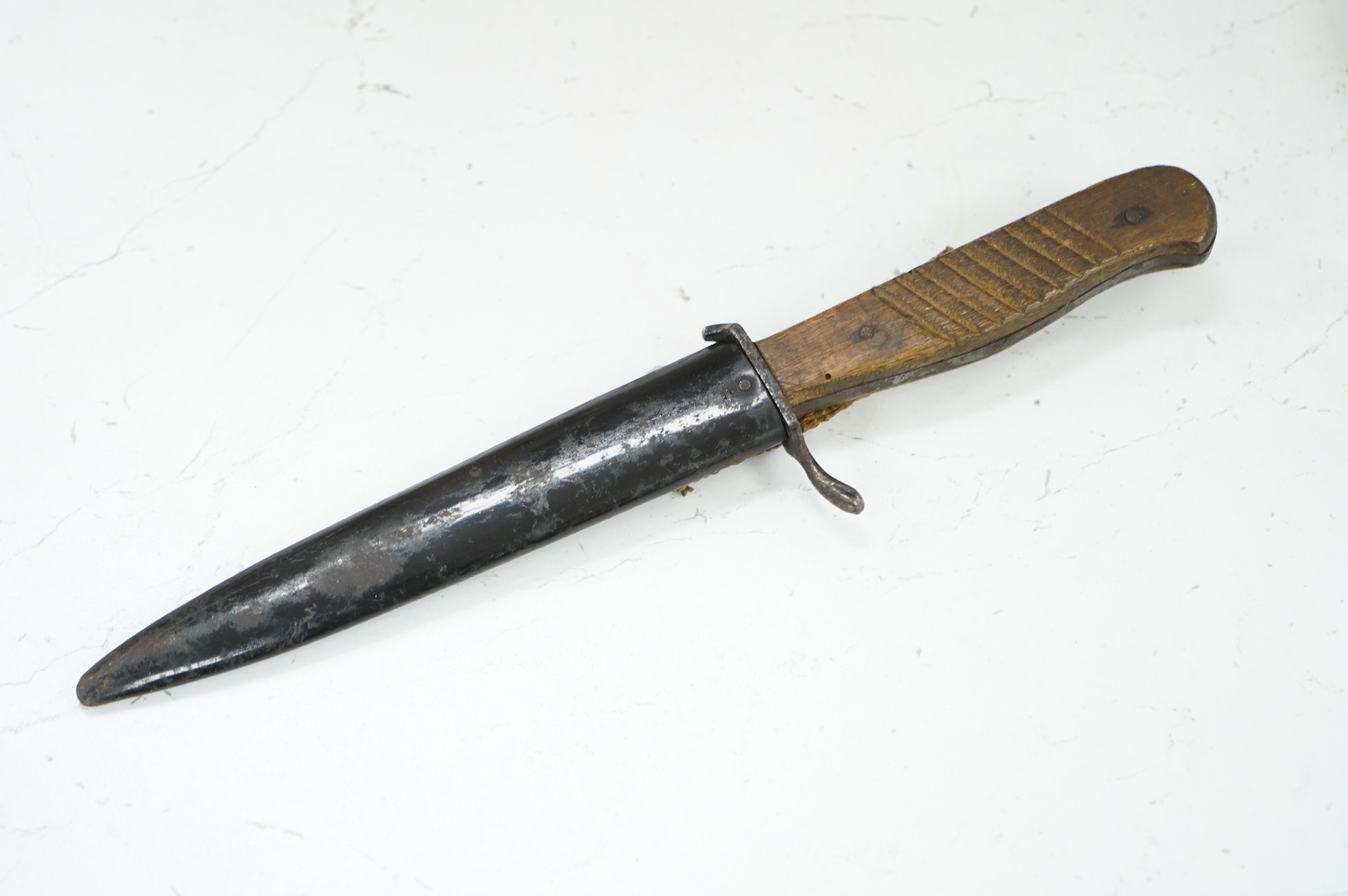 A First World War German Fighting Knife, with two piece wooden grip and steel cross guard, in original steel scabbard with canvas belt loop mount, single edged unmarked blade, blade 14cm, overall 25.5cm.